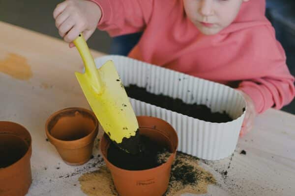 Mains d'enfants mettant de la terre dans un pot